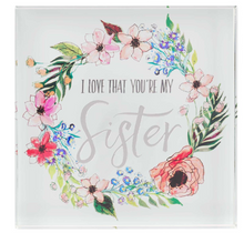 Load image into Gallery viewer, beautiful glass plaque that states &quot;I love that you&#39;re my sister&quot;.  Perfect inspiration for your sister.  Decor for home or office.  Can stand alone. Great for desk or shelf.  She&#39;ll love it.  Your sister will love it. Encased in etched flowers.
